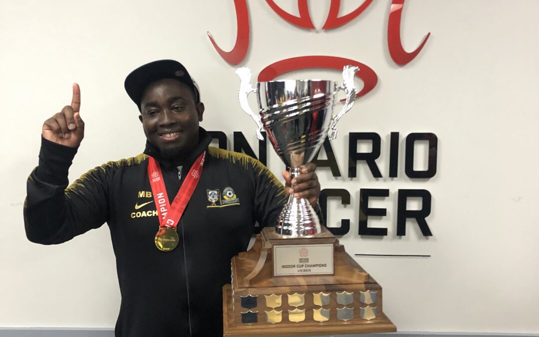 Man proudly holding a large trophy wearing a medal.