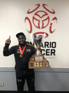 Man proudly holding a large trophy wearing a medal.