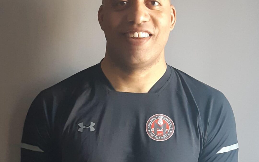 A man in black shirt standing next to wall.