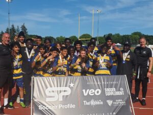 A jubilant football team celebrating a victory behind a banner at a stadium.