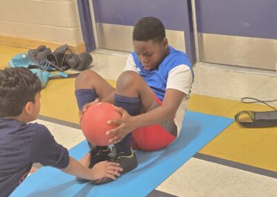 Two boys exercising together on a gym mat indoors.