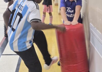 Child kicking a padded training shield indoors.