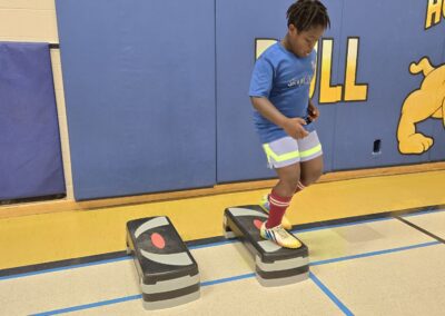 A boy jumping between stepping stones in a gym.