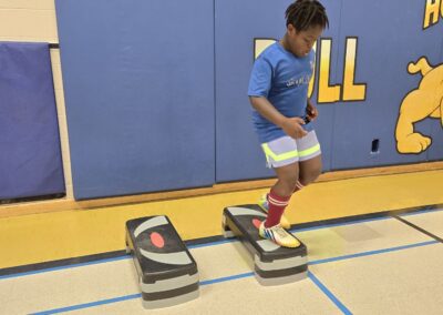 Boy stepping on exercise pads in a gym.
