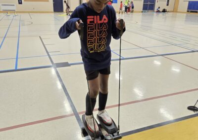 A boy testing a robot on a gym floor using a remote control.