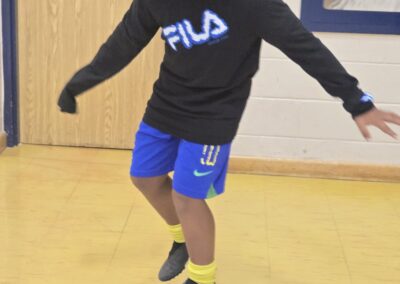 A boy balancing on a blue exercise ball indoors.