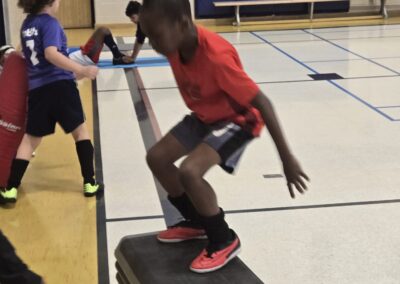 Child jumping onto a gym bench during a sports activity.