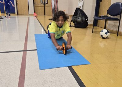 Child playing with a toy car on a blue mat indoors.