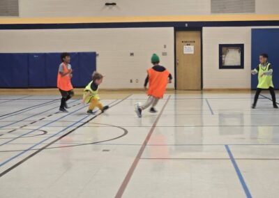 Children playing indoor soccer in a gymnasium.