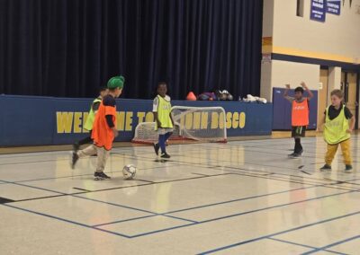 Children playing basketball in a school gymnasium.