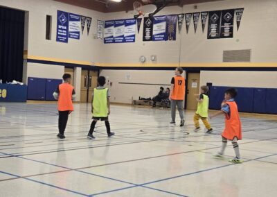 Children playing indoor volleyball in a gymnasium.