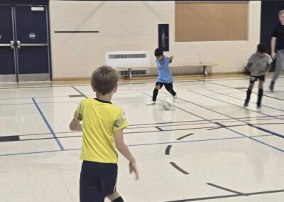 Children playing basketball indoors in a gymnasium.