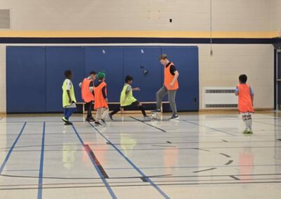 Children playing basketball indoors, one jumping to block a shot.