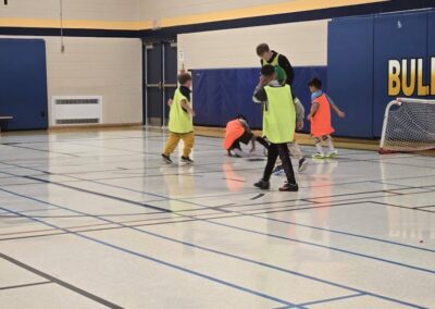 Children playing indoor soccer in a gymnasium.