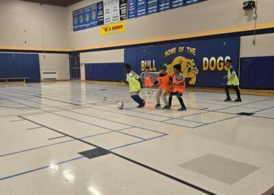 Kids playing indoor soccer in a school gymnasium.