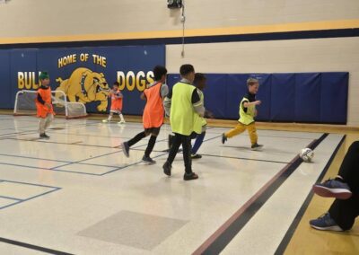 Kids playing indoor soccer in a gymnasium.