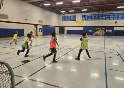 Children playing indoor soccer in a school gymnasium.