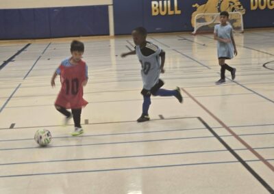 Children playing indoor soccer in a gymnasium.