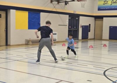 Two people practicing basketball moves in a gym.