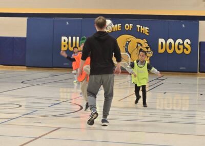 Children playing basketball indoors with a coach.