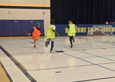 Three children running inside a gymnasium.