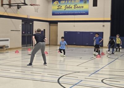 Children playing basketball in a gym with an adult coach.