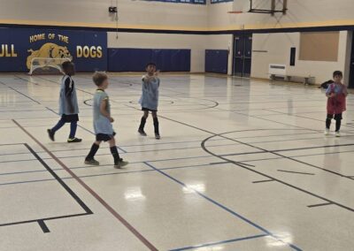 Young children walking across an indoor volleyball court in sports uniforms.