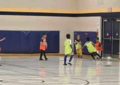 Kids playing indoor soccer in a gymnasium.