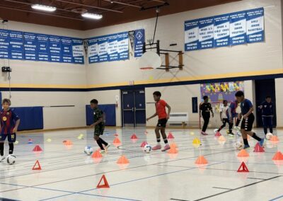People training in an indoor gym with cones and basketball hoops.
