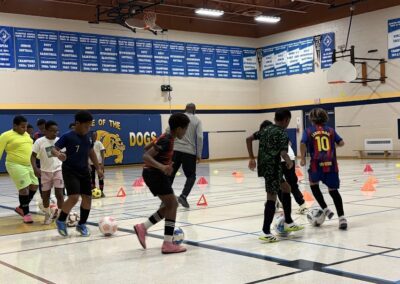 Young boys playing indoor soccer in a gymnasium.