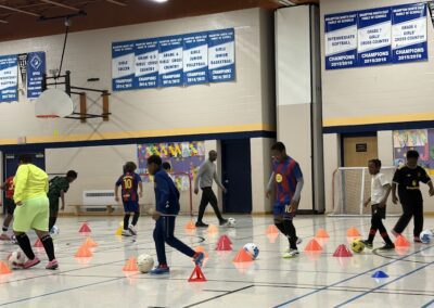 People practicing basketball drills in a gym with cones.