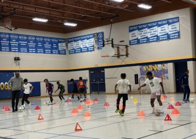 Children participating in an indoor basketball drill with cones.