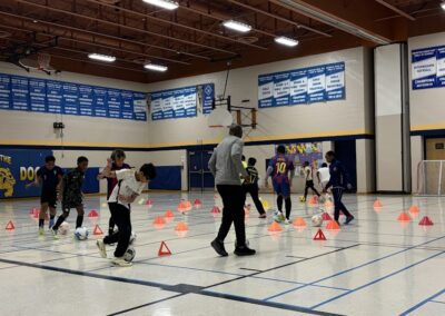 Children participating in a gym activity with cones and an instructor.