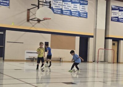 Children playing indoor soccer in a gymnasium.