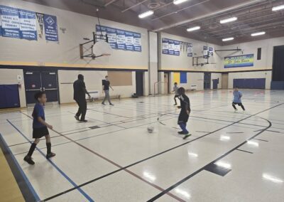 People playing pickleball in a gymnasium with multiple courts.