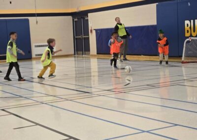 Children playing indoor soccer in a gymnasium.