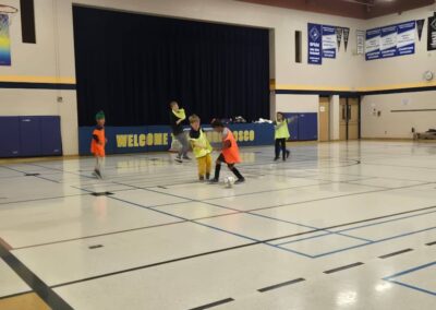 Children playing in a gym with a welcome banner.