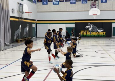 Young basketball players practicing dribbling in a gym.