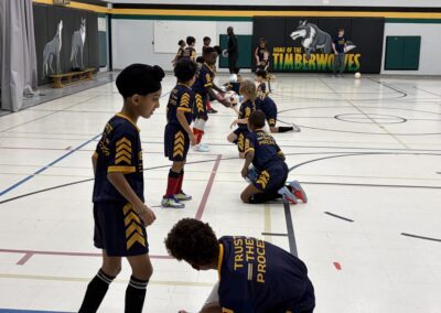 Youth soccer players lined up indoors, practicing with cones.