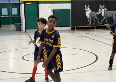 Two boys playing basketball indoors, one in blue and yellow jersey.