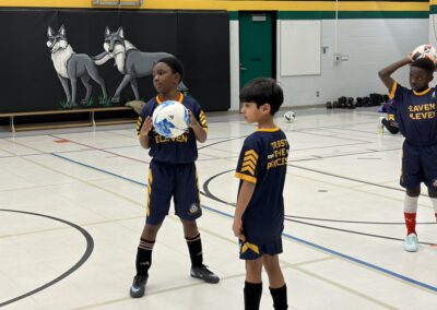 Two kids playing indoor soccer, one holding the ball.
