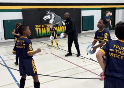Youth basketball players and coach in a gym during practice.