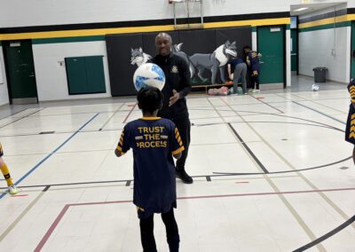 Children playing basketball in a gymnasium, one wearing a shirt that says 'Truth in the Schools'.