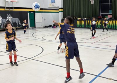 Youth volleyball player serving the ball indoors.