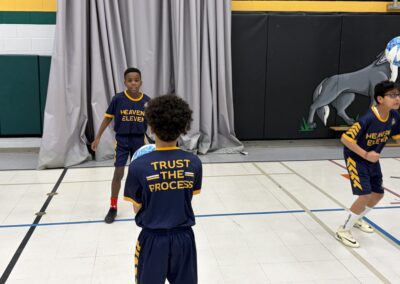Children playing basketball indoors wearing matching navy and yellow uniforms.