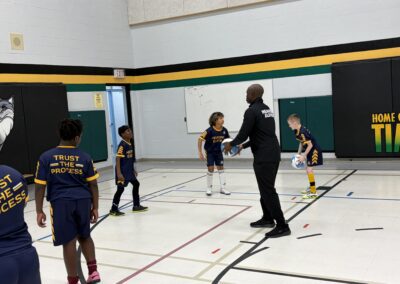 Children playing basketball indoors with a coach.