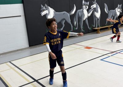 Boy playing basketball indoors, pointing while standing on court.