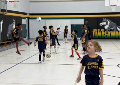 Kids playing indoor soccer in matching jerseys.