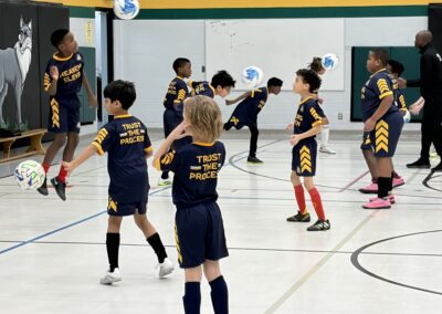 Kids practicing basketball drills indoors in team uniforms.