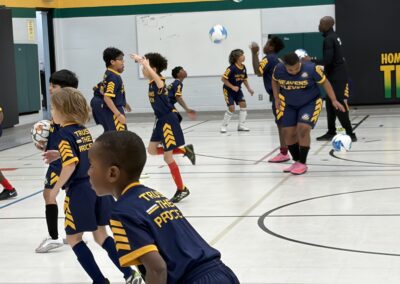 Children playing indoor soccer in a gymnasium.